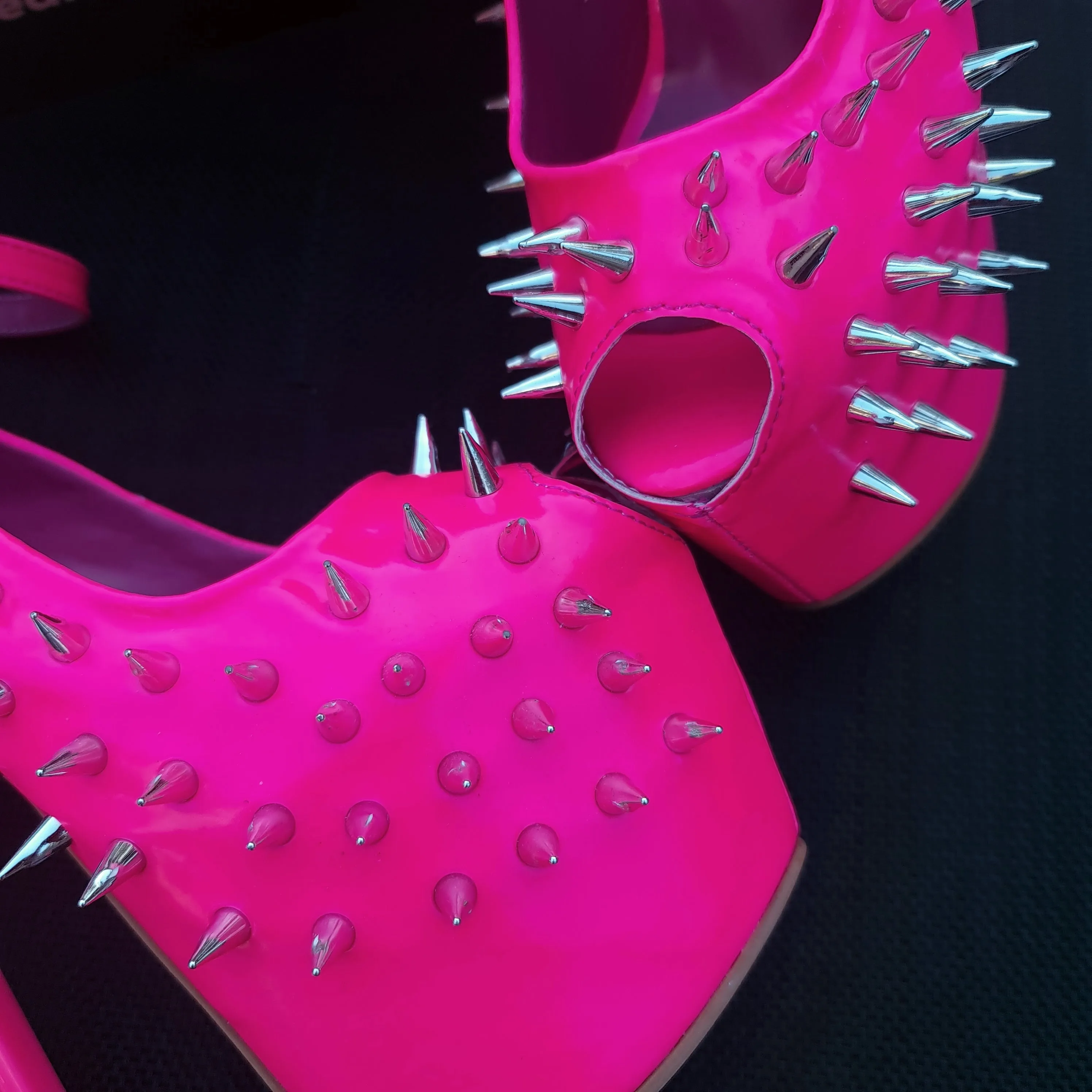 Glossy hot neon pink ankle strap heels with spike studs.