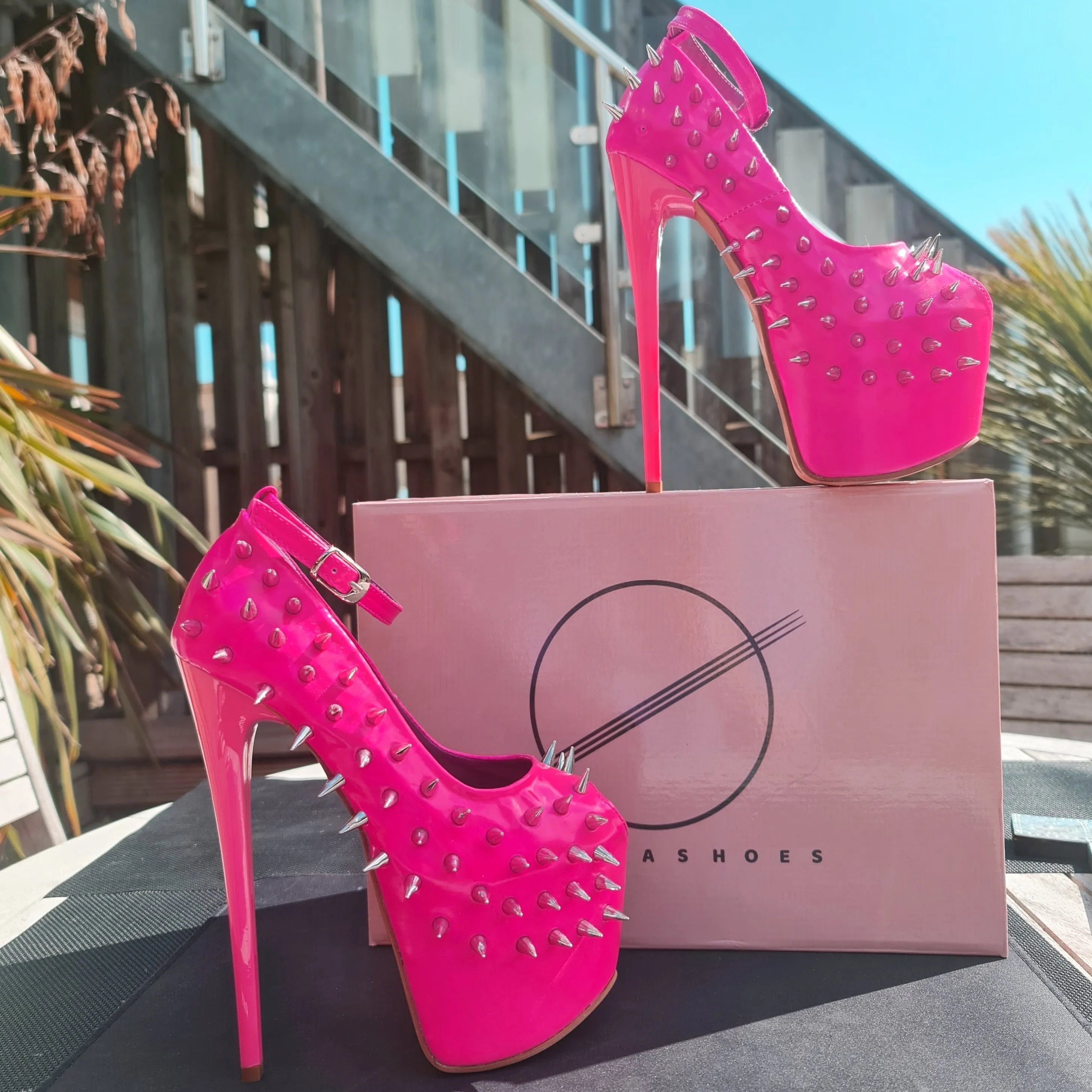 Glossy hot neon pink ankle strap heels with spike studs.